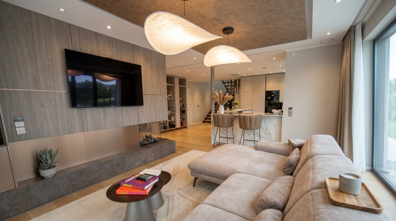 Wohnzimmer mit TV-Wand nach Maß, integriertem Kamin und offenem Übergang zur Küche